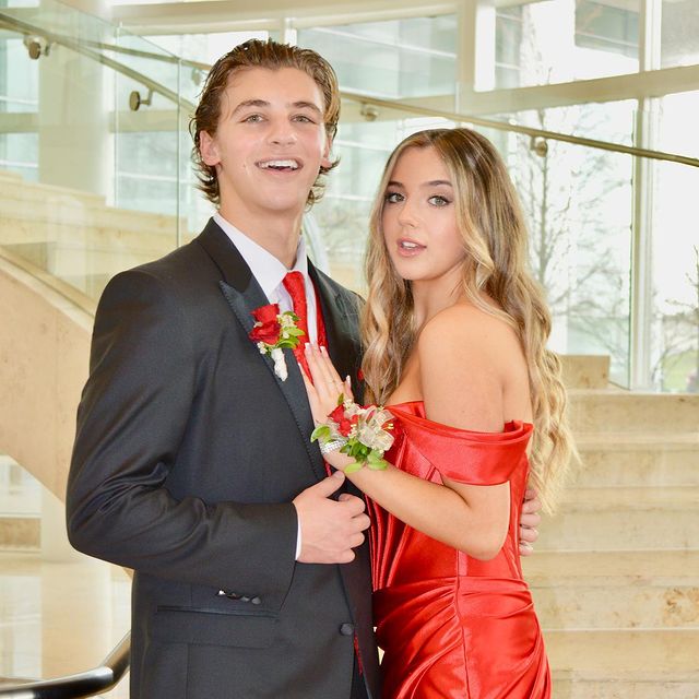 Alexa Nisenson posing with Giovanni Mazza wearing red dress and in a grey hair